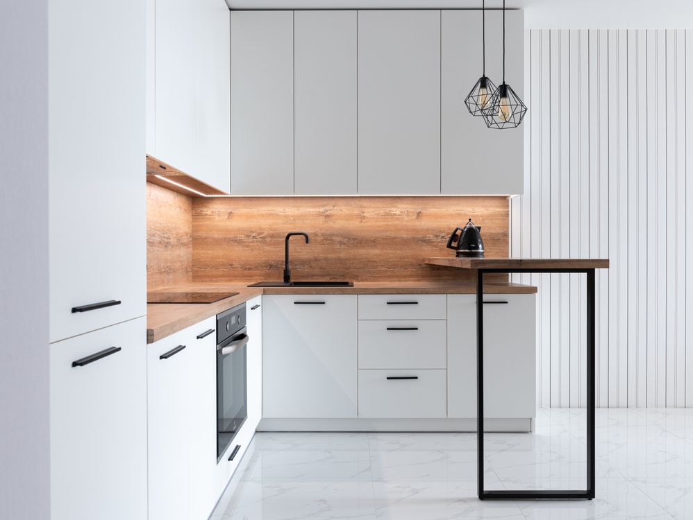 Cocina moderna reformada con armarios blancos y encimera clara